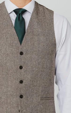 Brown herringbone tweed waistcoat worn with a white shirt and dark green tie.
