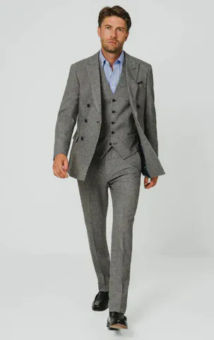 Model wearing a grey tweed three-piece suit with a light blue shirt and black shoes.