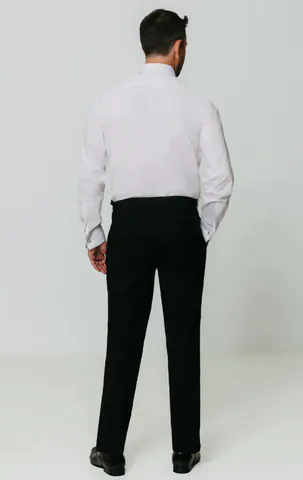 Back view of a model wearing a white dress shirt tucked into black trousers.